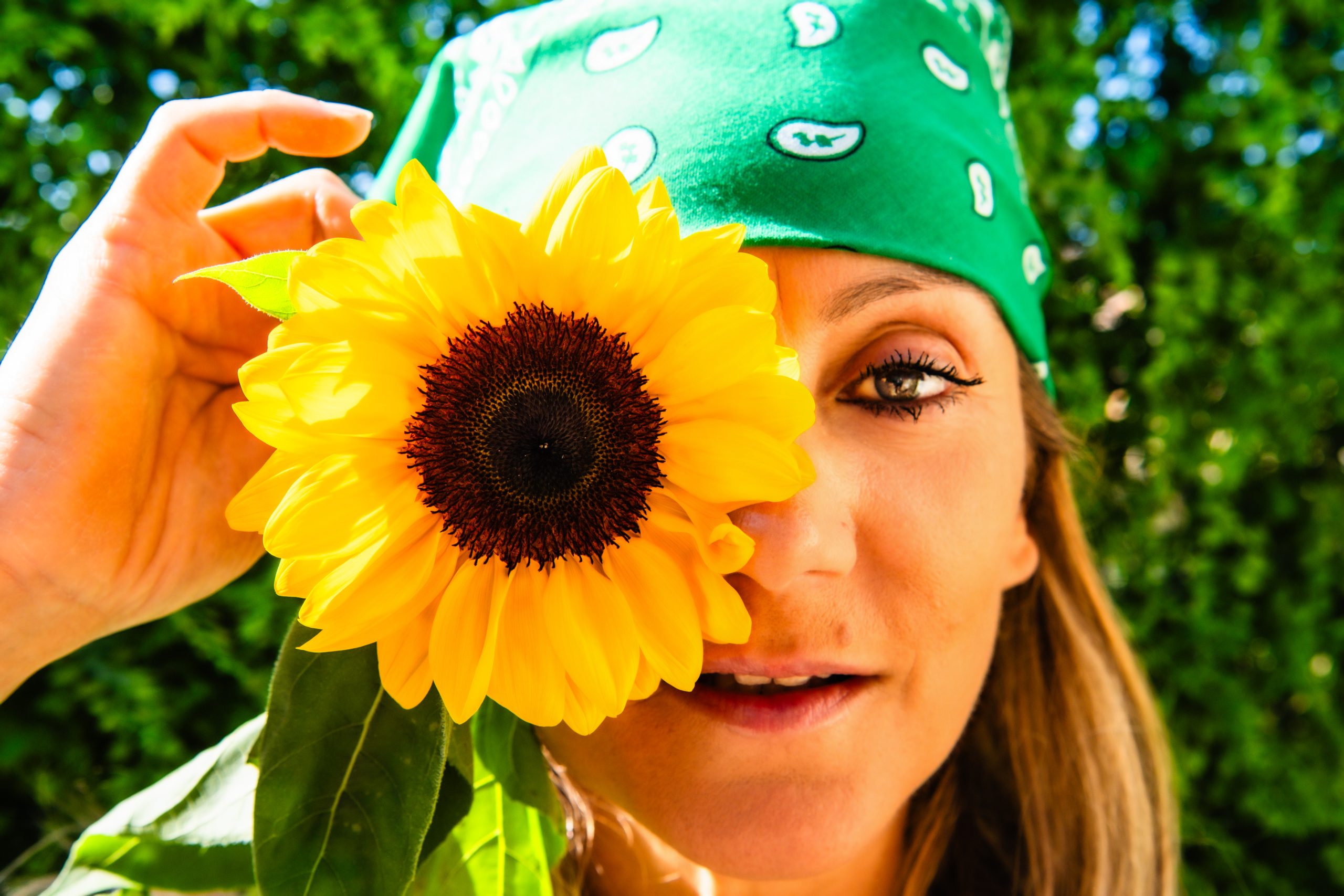 Francesca tenant un tournesol devant son visage, regardant la caméra.